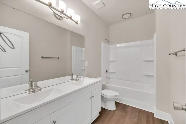 a bathroom with a bathtub shower sink vanity mirror and toilet