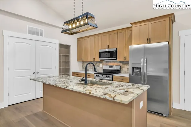 a kitchen with kitchen island granite countertop a sink appliances counter top space and cabinets