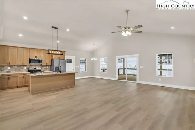 a large kitchen with stainless steel appliances kitchen island a large counter top and a wooden floors
