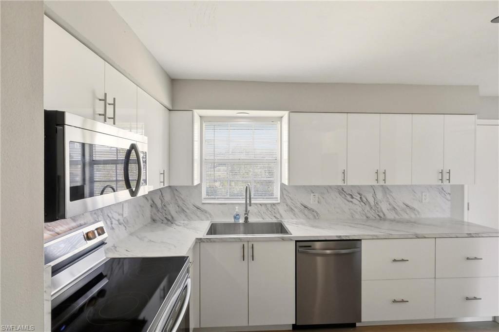 3325 Airport Road North, Unit S8 Naples, FL 34105 - Photo 10 of 33 a kitchen with stainless steel appliances granite countertop a sink stove and cabinets