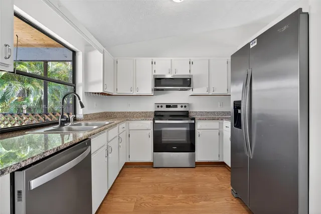 a kitchen with stainless steel appliances granite countertop a refrigerator sink and stove