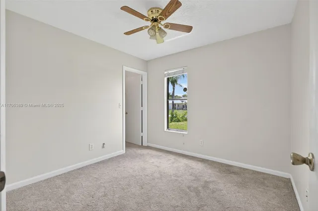 an empty room with windows and ceiling fan