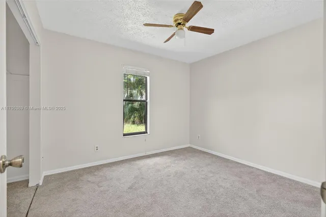 an empty room with windows and ceiling fan