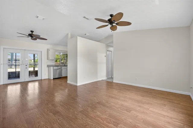 a view of empty room with wooden floor and ceiling fan