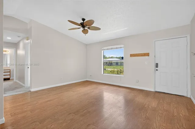 an empty room with wooden floor fan and windows