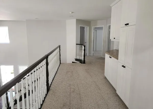 a view of a hallway with wooden floor and staircase