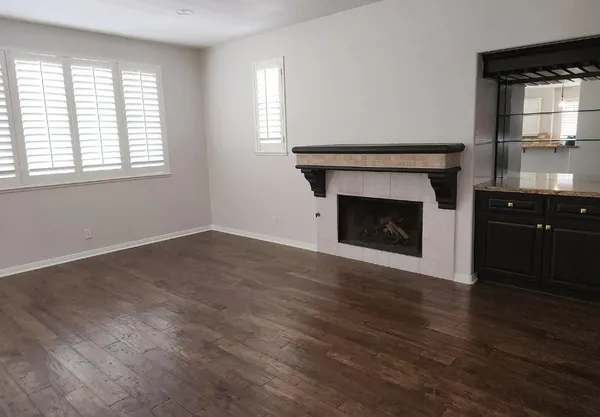 an empty room with wooden floor fireplace and windows