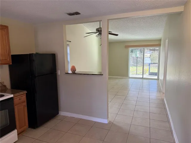 a view of a refrigerator in kitchen and an empty room in wooden floor