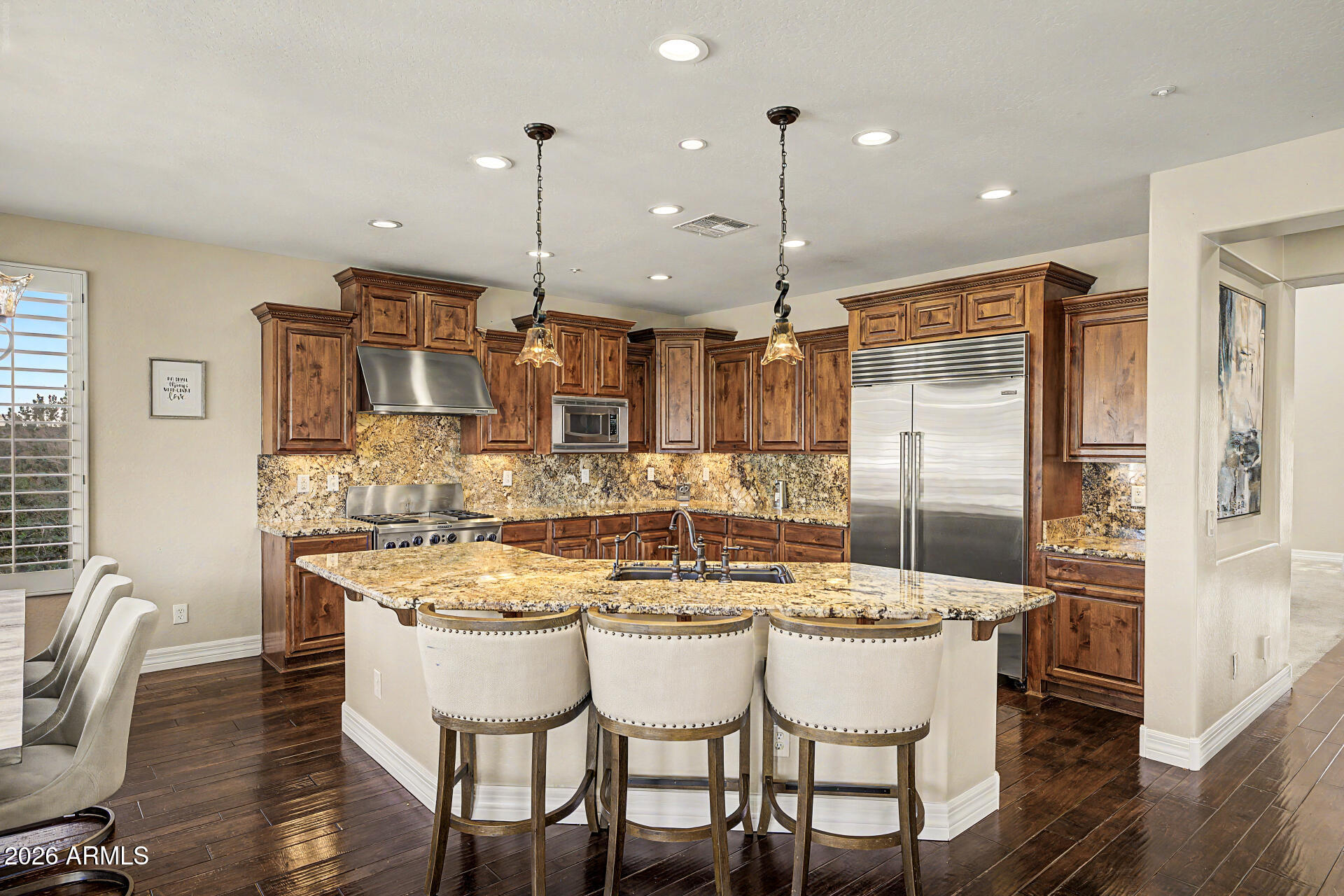 13058 West Lowden Road Peoria, AZ 85383 - Photo 30 of 122 a kitchen with stainless steel appliances kitchen island granite countertop a dining table chairs and white cabinets