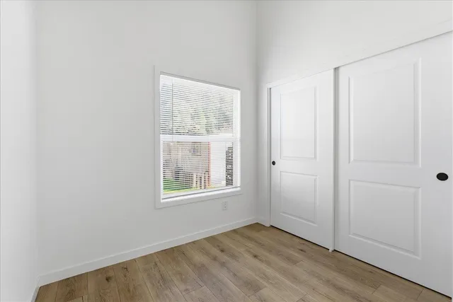 an empty room with wooden floor and windows