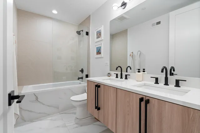 a bathroom with a double vanity sink toilet mirror and bathtub