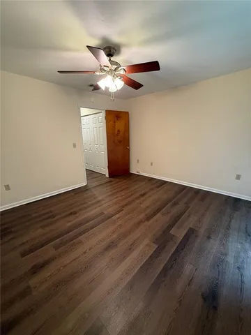 a view of an empty room with wooden floor and a ceiling fan