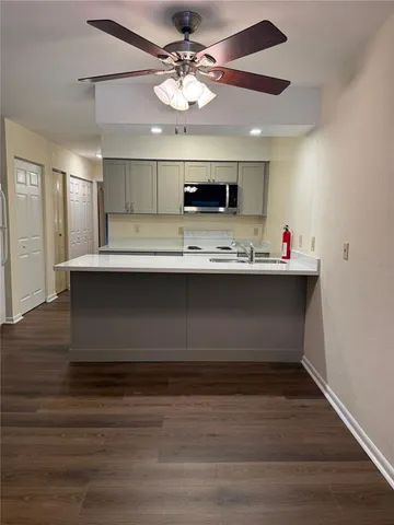 a view with kitchen island a sink wooden floor and a ceiling fan