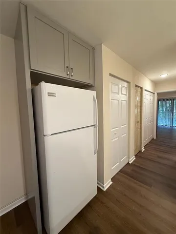 a white refrigerator freezer and a wooden floor in a room
