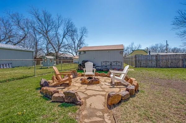 a view of a backyard with table and chairs potted plants and large tree