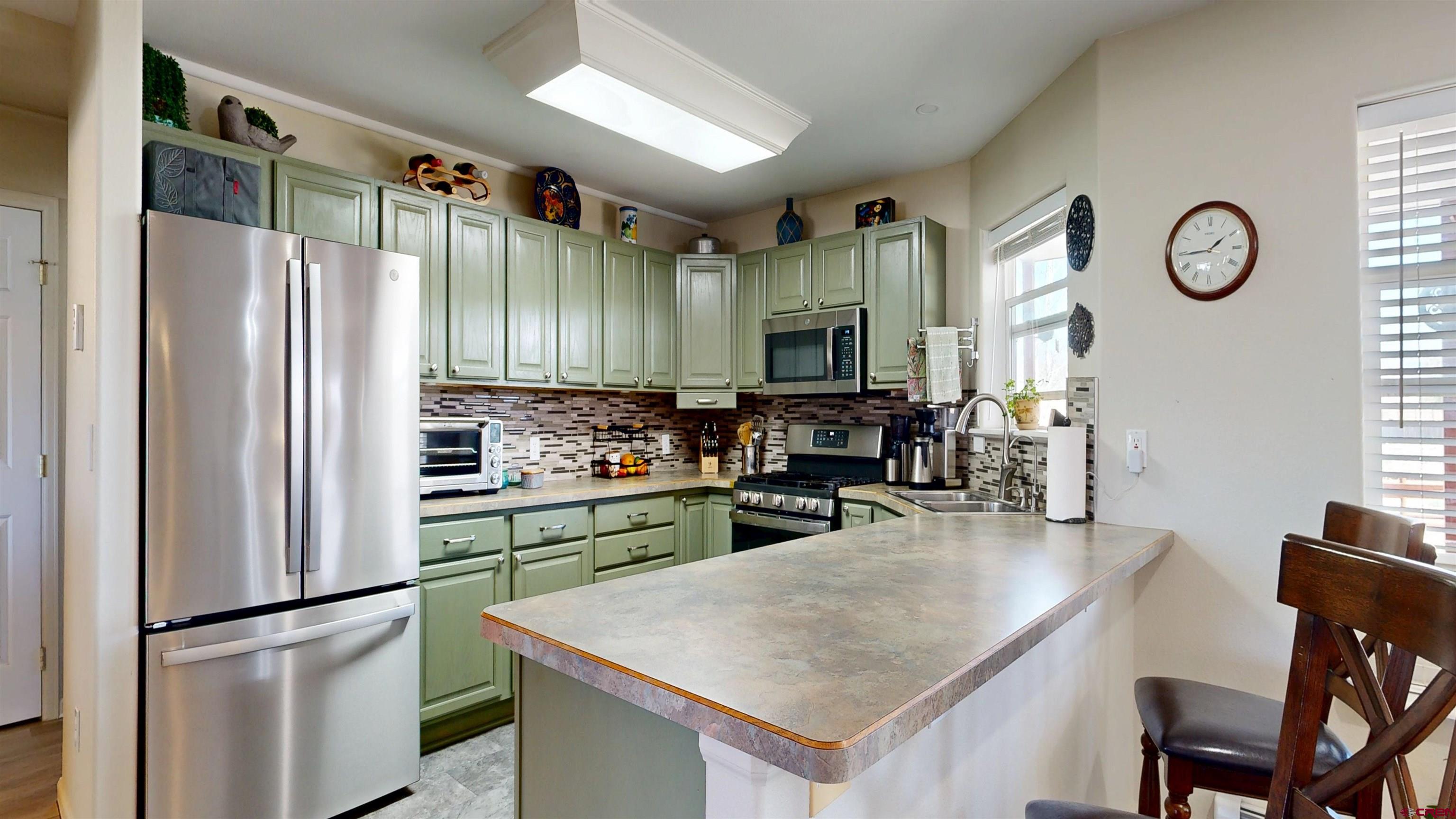 62940 Jeremy Road Montrose, CO 81401 - Photo 8 of 44 a kitchen with stainless steel appliances granite countertop a refrigerator a stove and a sink with wooden floor