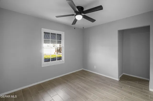 an empty room with window and ceiling fan