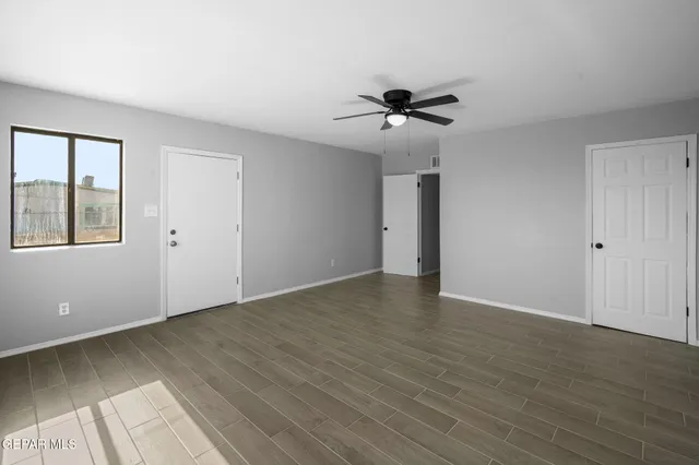 a view of empty room with wooden floor and fan