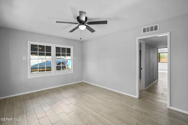 a view of empty room with wooden floor and fan