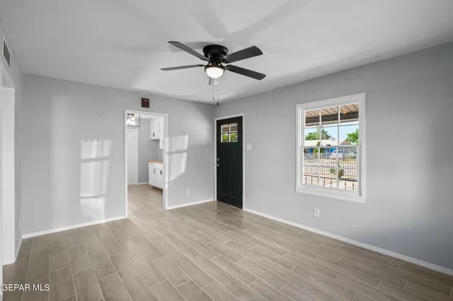 a view of an empty room with wooden floor and a window