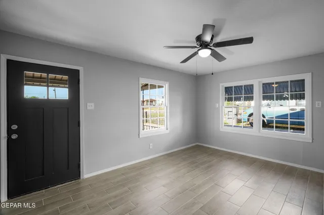 a view of empty room with wooden floor and fan