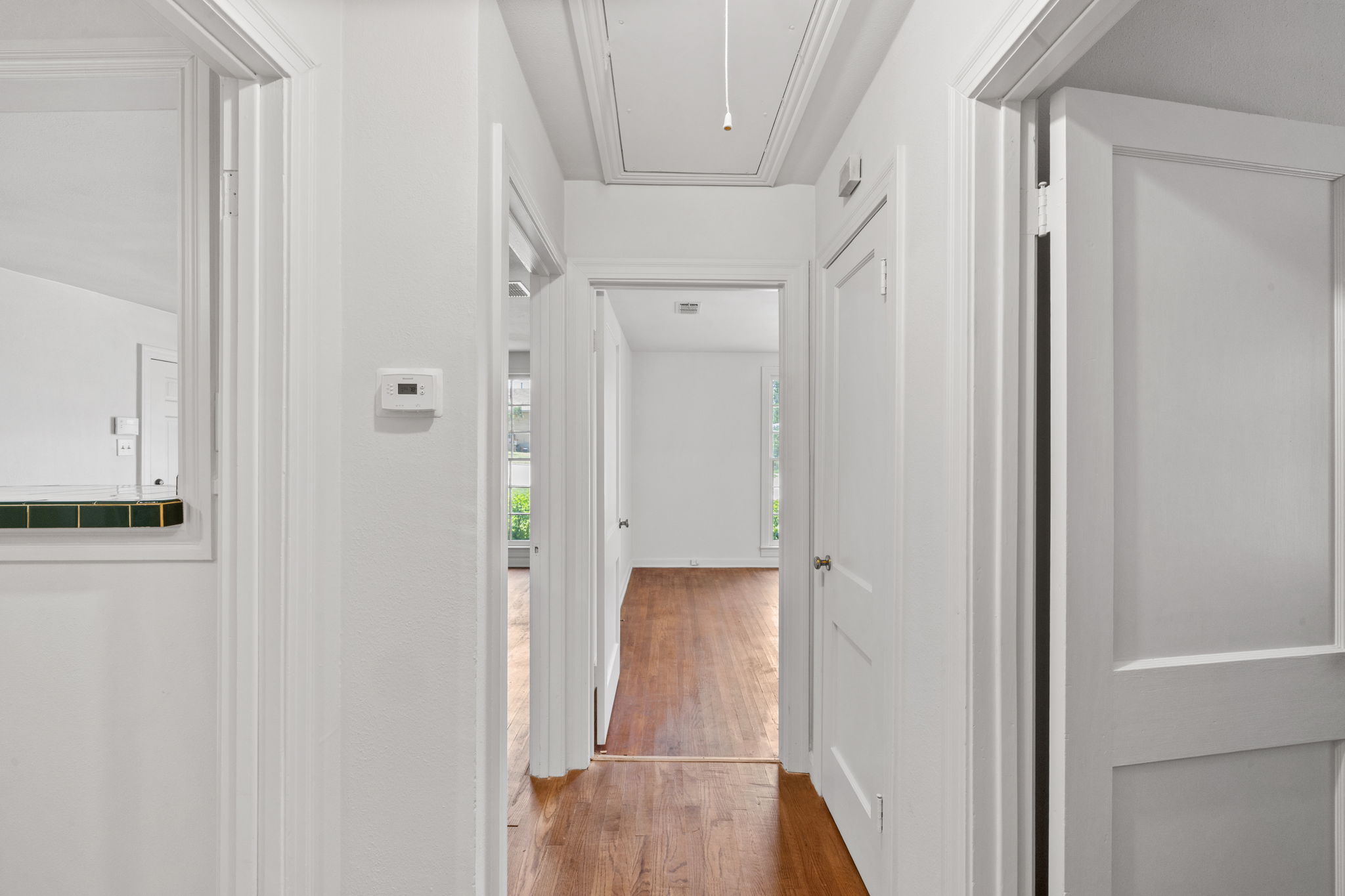 3704 Cherrywood Road Austin, TX 78722 - Photo 23 of 40 A pristine hallway with original hardwood flooring leads to inviting, sun-filled rooms.