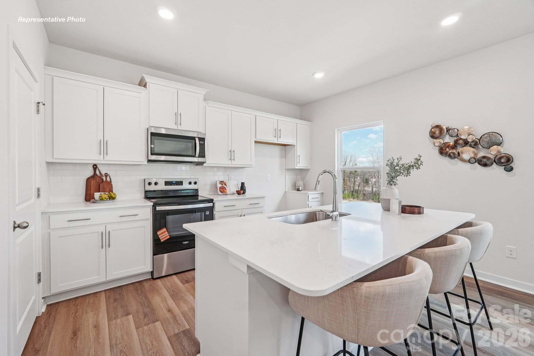 7600 Bainbridge Road Sherrills Ford, NC 28673 - Photo 10 of 39 a kitchen with a sink a stove a refrigerator and white cabinets with wooden floor