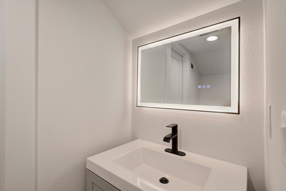 2220 Yellow Jacket Lane, Unit 1 Austin, TX 78741 - Photo 32 of 35 A well-lit vanity area boasts a contemporary sink and an illuminated mirror with touch controls.