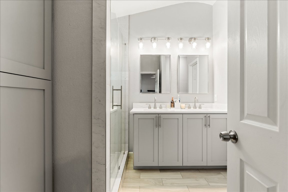 4456 Mather Kyle, TX 78640 - Photo 13 of 25 Bathroom featuring a stall shower, double vanity, wood tiled floors, and vaulted ceiling