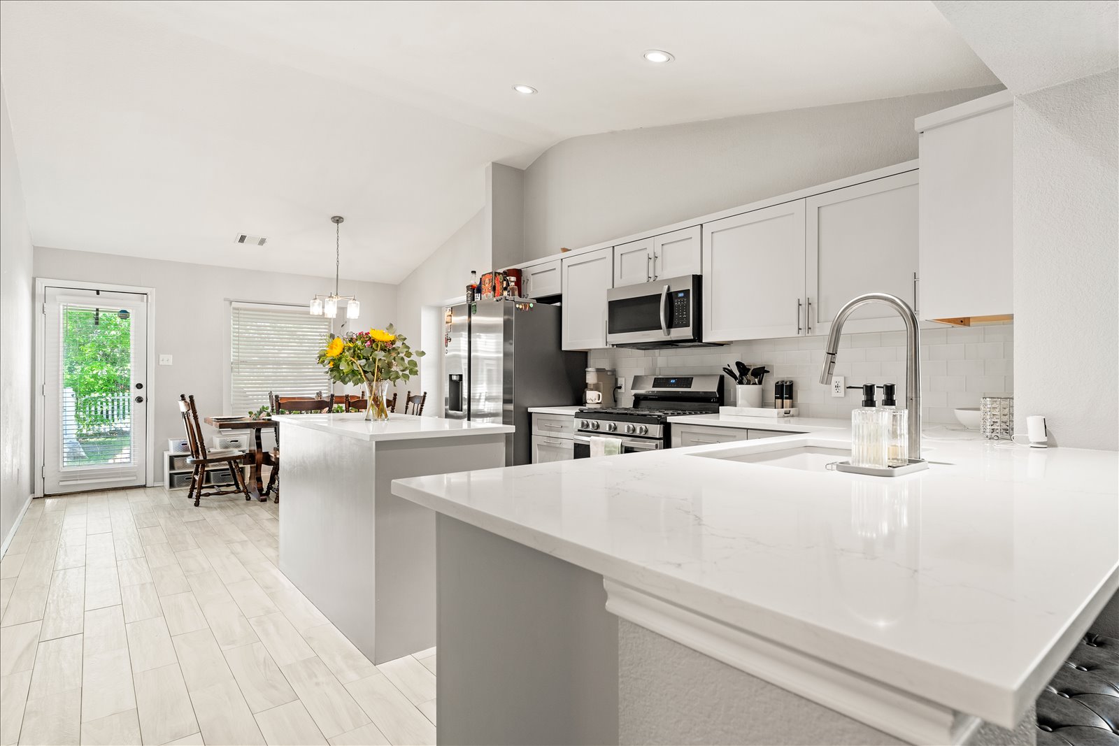 4456 Mather Kyle, TX 78640 - Photo 7 of 25 Kitchen featuring a kitchen island, stainless steel appliances, white cabinets, hanging light fixtures, and vaulted ceiling