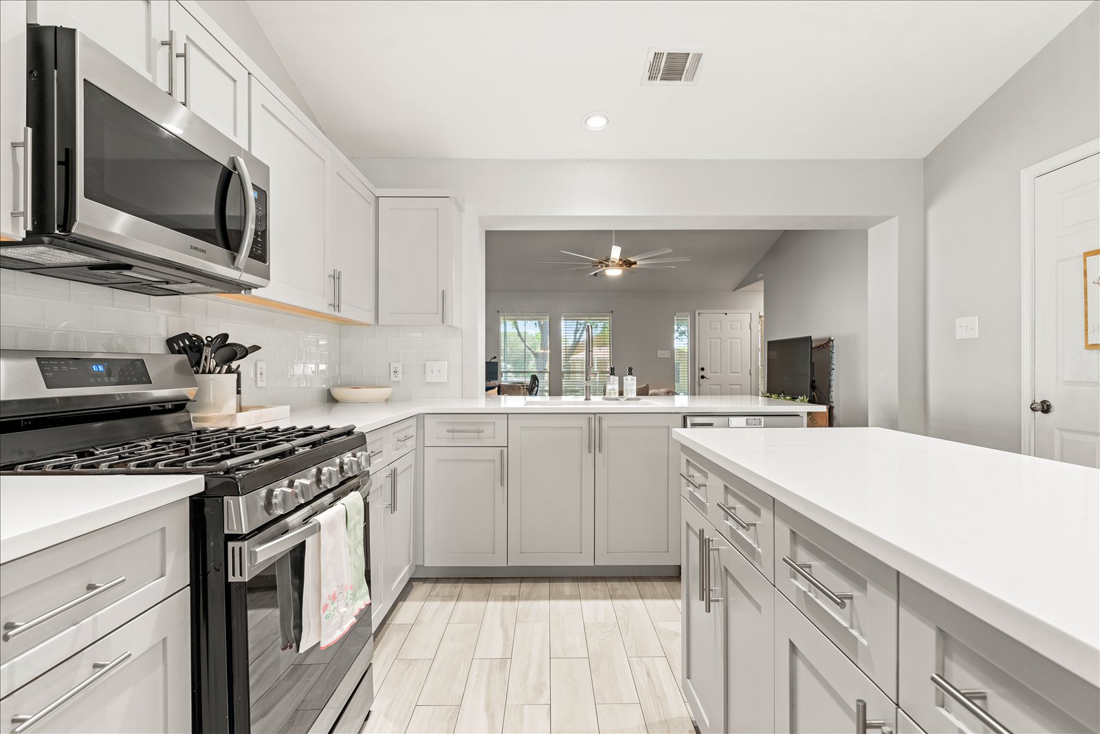 4456 Mather Kyle, TX 78640 - Photo 8 of 25 Kitchen with stainless steel appliances, a peninsula, decorative backsplash, white cabinetry, and recessed lighting