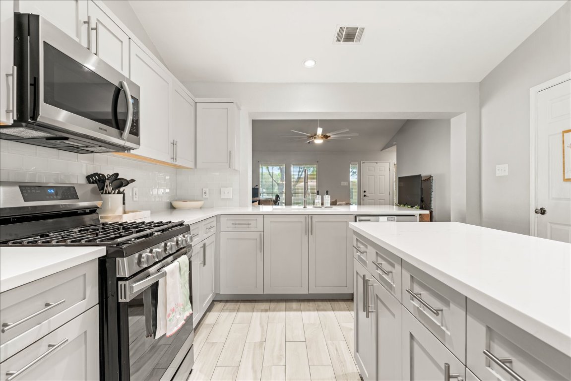 4456 Mather Kyle, TX 78640 - Photo 8 of 25 Kitchen with stainless steel appliances, a peninsula, decorative backsplash, white cabinetry, and recessed lighting