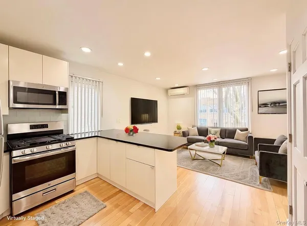 a living room with stainless steel appliances furniture a flat screen tv and a window