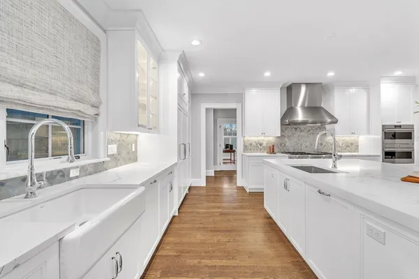 a large white kitchen with kitchen island granite countertop a large counter top a sink stainless steel appliances and a window