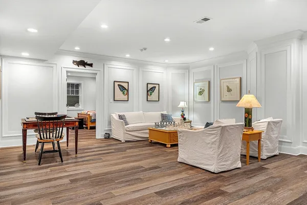 a living room with furniture a lamp and wooden floor