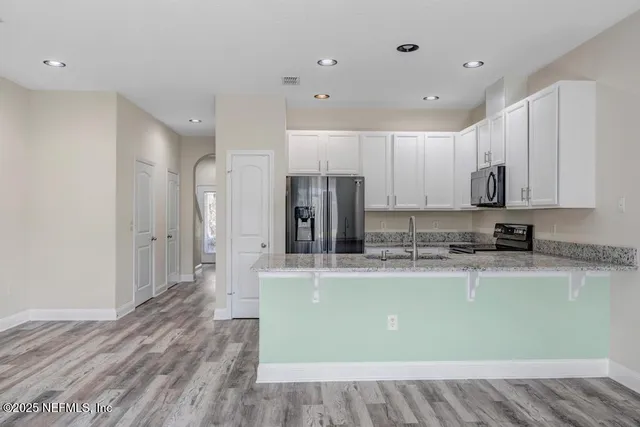 a large kitchen with stainless steel appliances granite countertop a stove a sink and a refrigerator