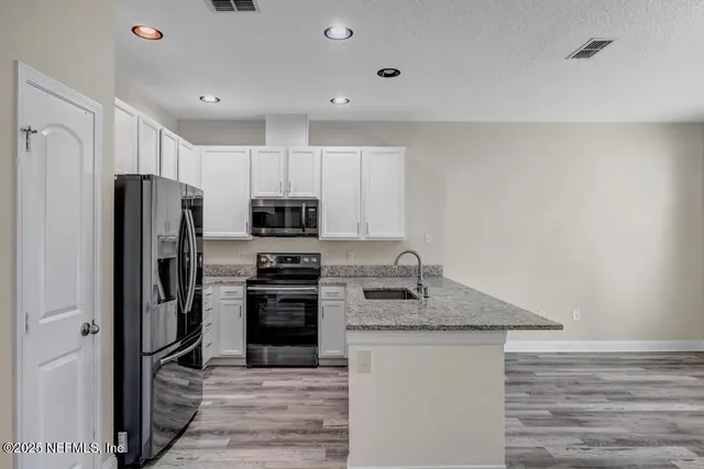 a kitchen with stainless steel appliances granite countertop a refrigerator a stove top oven a sink and dishwasher