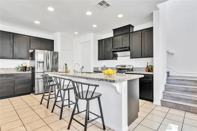 a kitchen with stainless steel appliances kitchen island granite countertop a refrigerator and a stove top oven