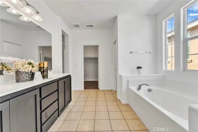 a en suite spacious bathroom with a tub double vanity and view of living room