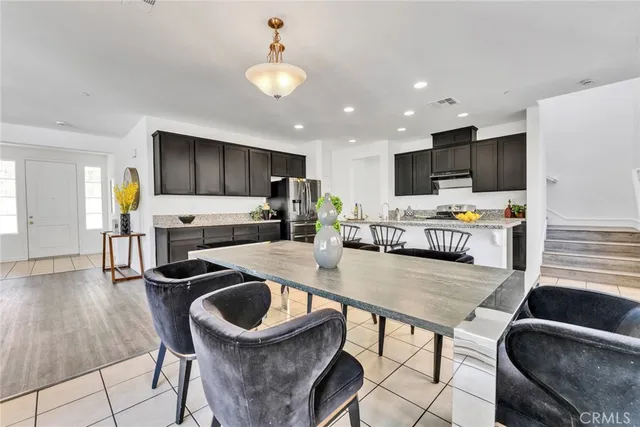 a kitchen with stainless steel appliances granite countertop a stove top oven a refrigerator a sink and a dining table with wooden floor