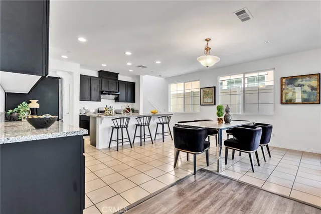 a kitchen with stainless steel appliances granite countertop a stove a refrigerator a kitchen island a dining table and chairs with wooden floor