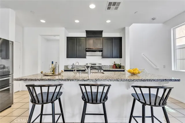 a kitchen with stainless steel appliances granite countertop a table chairs sink and microwave