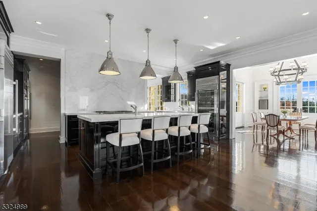 a dining room with stainless steel appliances kitchen island granite countertop a table chairs and a kitchen view