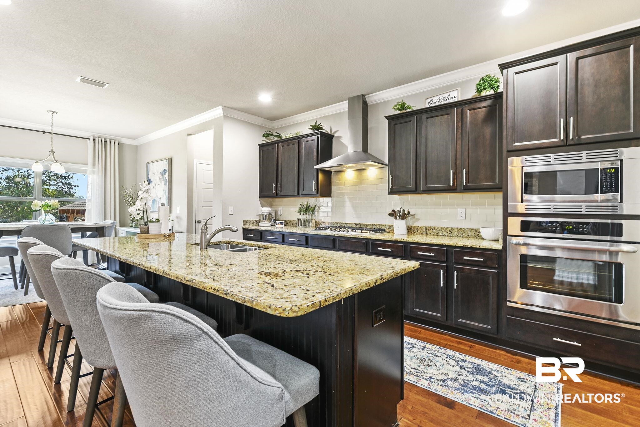 31500 Spoonbill Road Daphne, AL 36527 - Photo 17 of 85 Kitchen with stainless steel appliances, wall chimney exhaust hood, an island with sink, and dark wood-type flooring