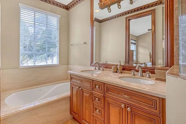 a bathroom with a granite countertop sink mirror and a bathtub