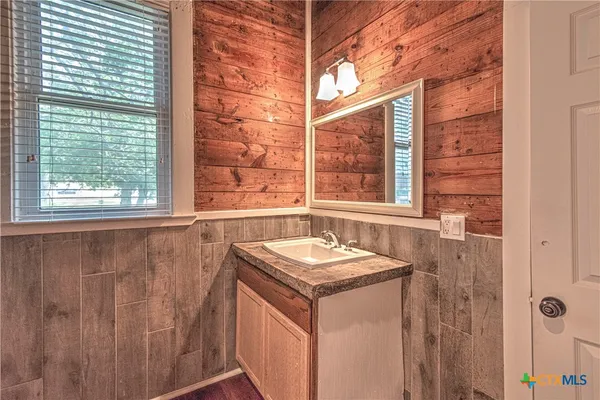 a bathroom with a granite countertop sink and a window