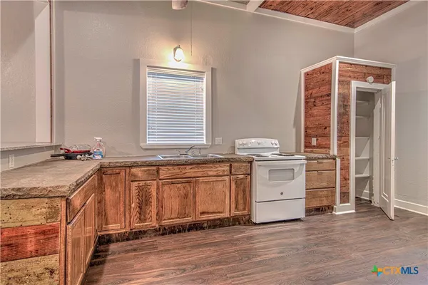 a room with granite countertop a sink and a stove top oven