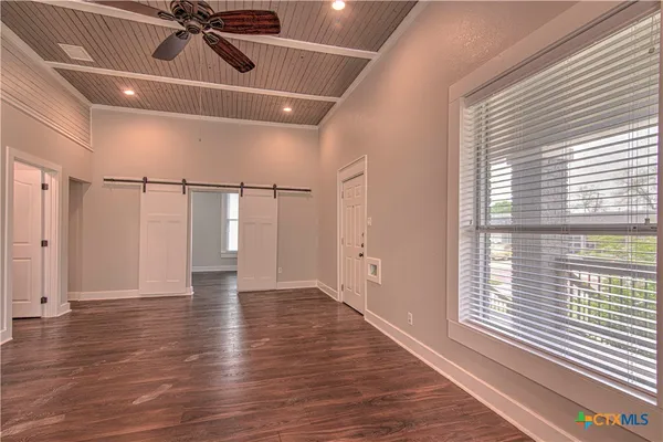 a view of an empty room with wooden floor and a window