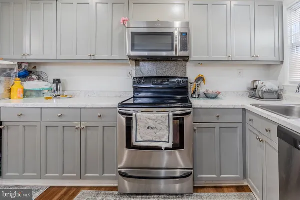 a kitchen with stainless steel appliances granite countertop a stove and a white cabinets