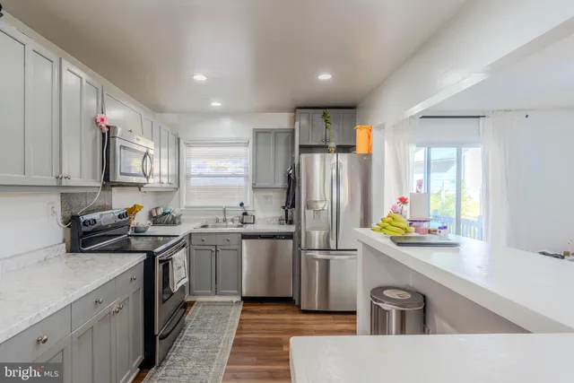 a kitchen with stainless steel appliances a sink a stove a refrigerator cabinets and a window